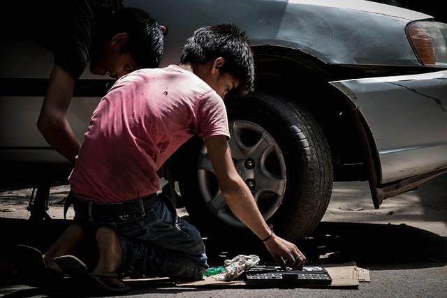 Criança trocando a roda de um carro