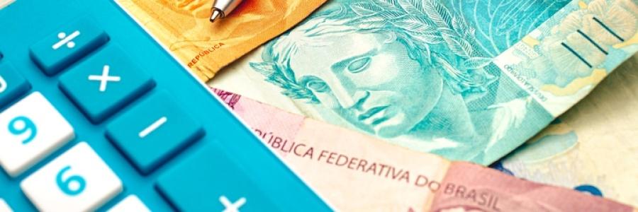 Calculadora, moedas e maços de cédulas de real