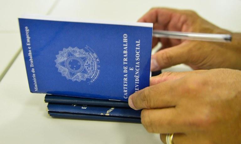 Homem assinando carteira de trabalho