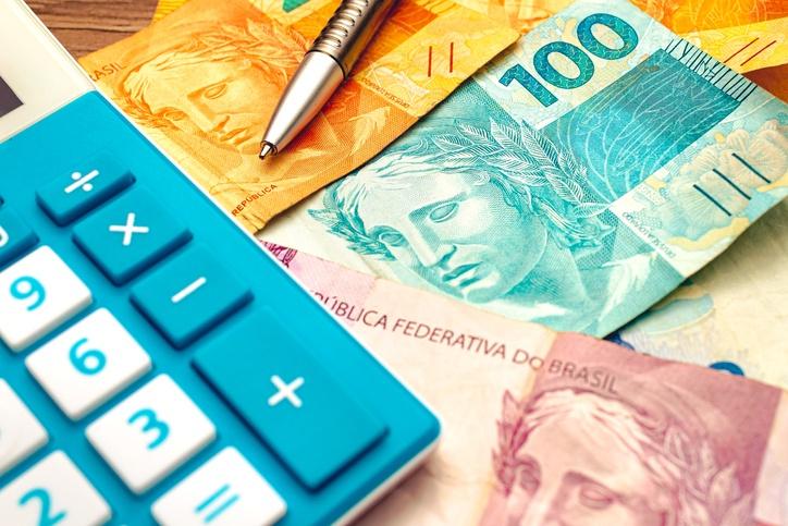 Calculadora, moedas e maços de cédulas de real