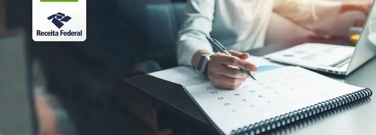 Mão segurando caneta sobre um calendário