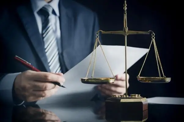 Advogado segurando contrato e uma caneta e uma balança da justiça a frente